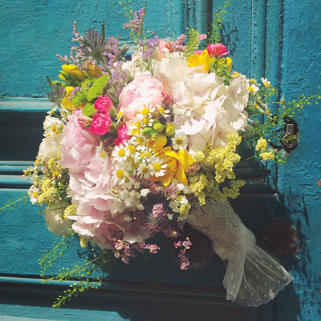 Ramo de novia silvestre y vaporoso en tonos rosas, blancos y amarillos, realizado con peonias, hortensia rosa, freesia y limonium