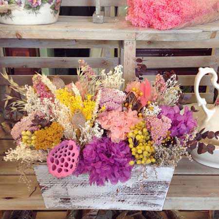 Caja de madera con flor seca y preservada en tonos lilas, amarillos y rosas