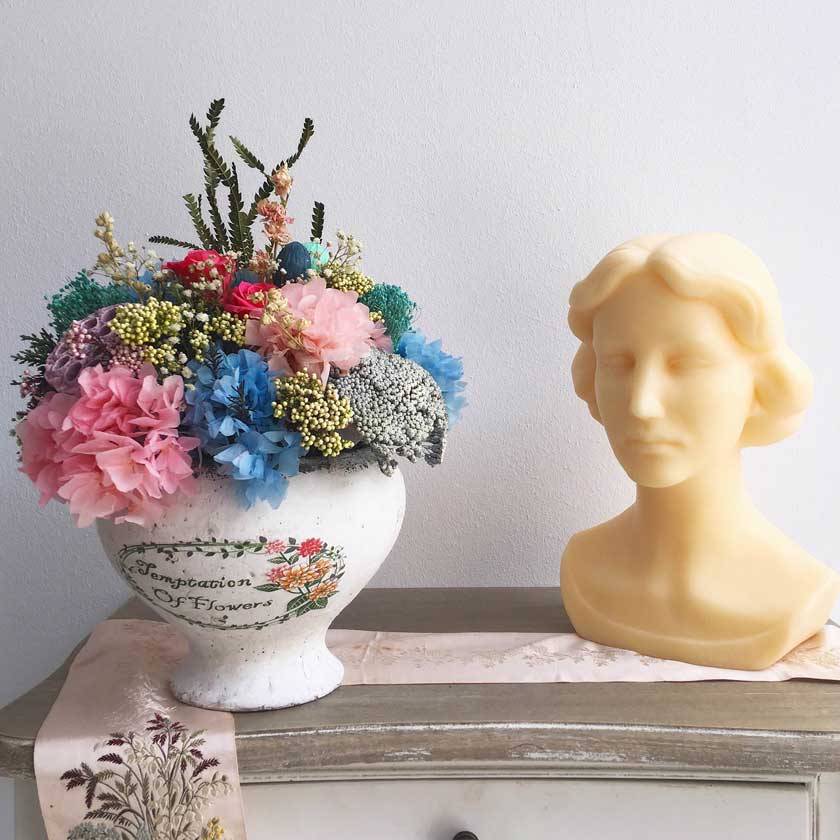 Centro en tonos azules y rosas, con flores secas y preservadas en recipiente de cerámica vintage.