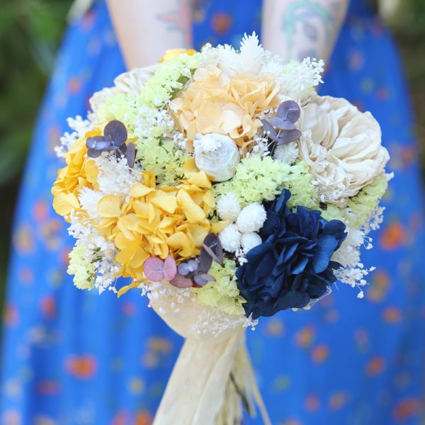Diferente y original ramo de novia preservado y seco en tonalidades ocres, naranjas, blancas, amarillas y con una nota azul.