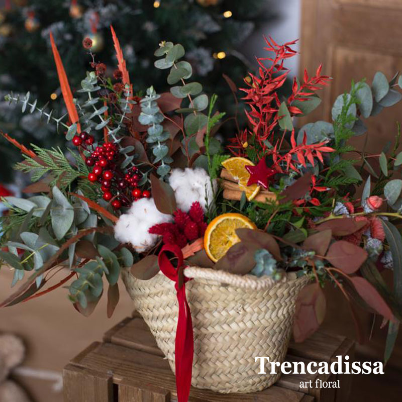 Composición natural realizada en un cesto de fibra natural decorado con motivos navideños.