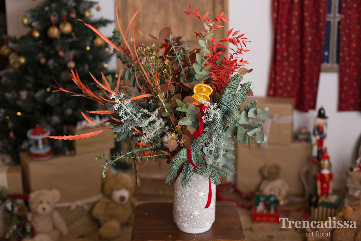 Ramo de navidad natural en un jarrón de cemento con notas navideñas, ideal para decorar y perfumar cualquier espacio.