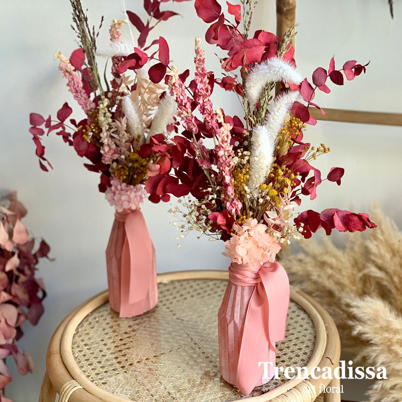 Jarrones de cristal rosa con flores secas y preservadas