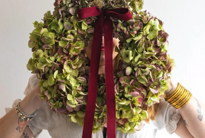 Corona realizada con hortensia natural que se deja secan con lazo de terciopelo granate.