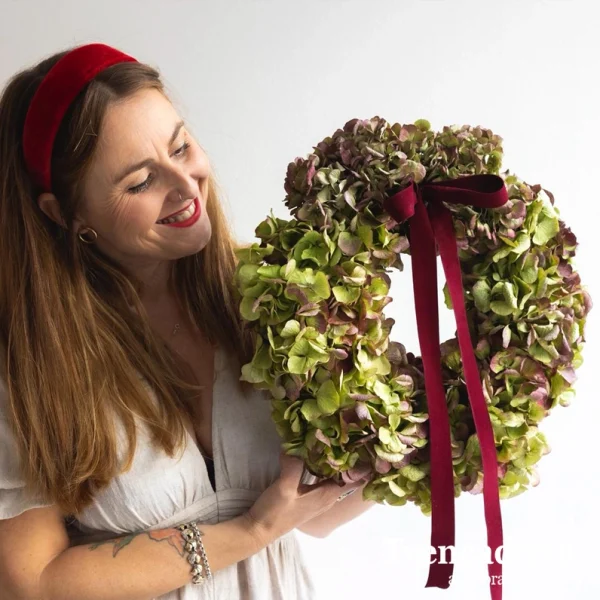 Corona realizada con hortensia natural que se deja secan con lazo de terciopelo granate.