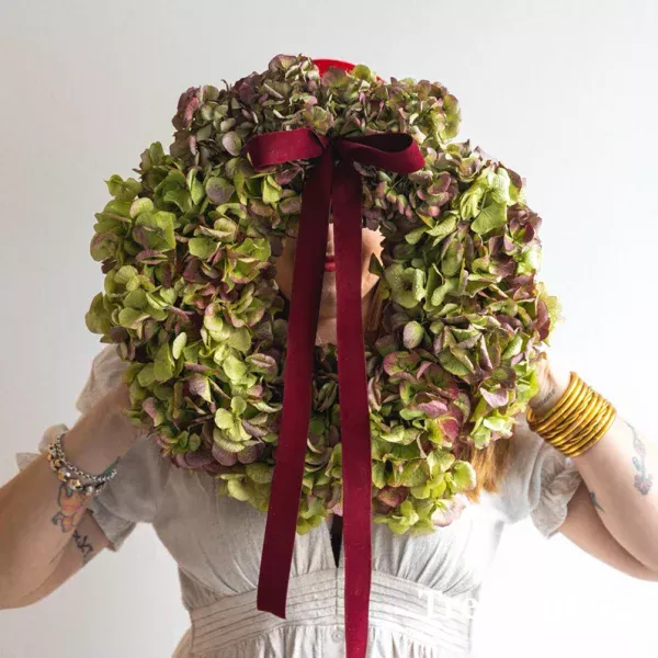 Corona realizada con hortensia natural que se deja secan con lazo de terciopelo granate.