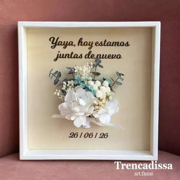 Marco personalizado de madera con flores secas y preservadas Creamos un marco único y artesanal, elaborado en madera y decorado con flores secas y preservadas en los mismos tonos que el ramo de la novia. Podrás personalizarlo con los nombres de los novios, la fecha especial y la frase que tú elijas para convertirlo en un recuerdo eterno. Para elegir los textos y los colores del ramillete, así como concretar cualquier detalle de tu diseño, ponte en contacto con nosotros. Estaremos encantados de ayudarte a crear una pieza tan especial como vuestro día.